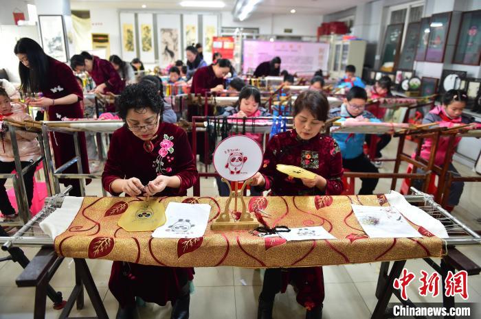 江西省級非遺豫章繡傳(chuan) 承人手把手指導小學生繡製2022年北京冬奧會(hui) 吉祥物“冰墩墩”形象。　喻雲(yun) 亮 攝