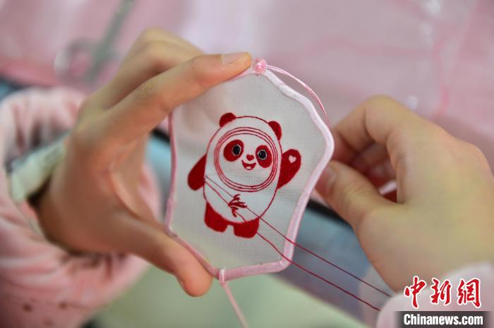 圖為(wei) 一名小學生正在繡製2022年北京冬奧會(hui) 吉祥物“冰墩墩”形象。　喻雲(yun) 亮 攝