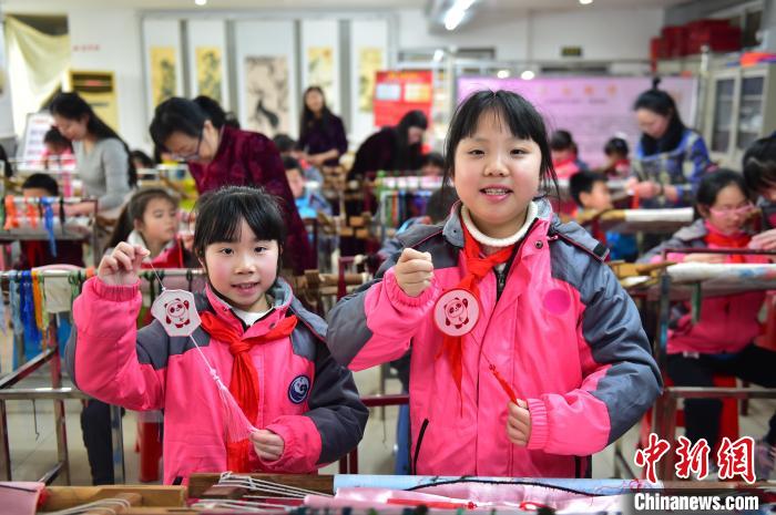 圖為(wei) 小學生展示繡製好的2022年北京冬奧會(hui) 吉祥物“冰墩墩”形象。　喻雲(yun) 亮 攝
