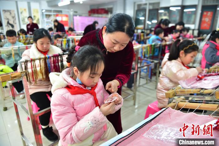 江西省級非遺豫章繡傳(chuan) 承人手把手指導小學生繡製2022年北京冬奧會(hui) 吉祥物“冰墩墩”形象。　喻雲(yun) 亮 攝