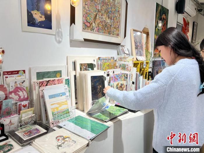圖為(wei) 藝術品商店內(nei) ，顧客挑選插畫作品。　鍾旖 攝