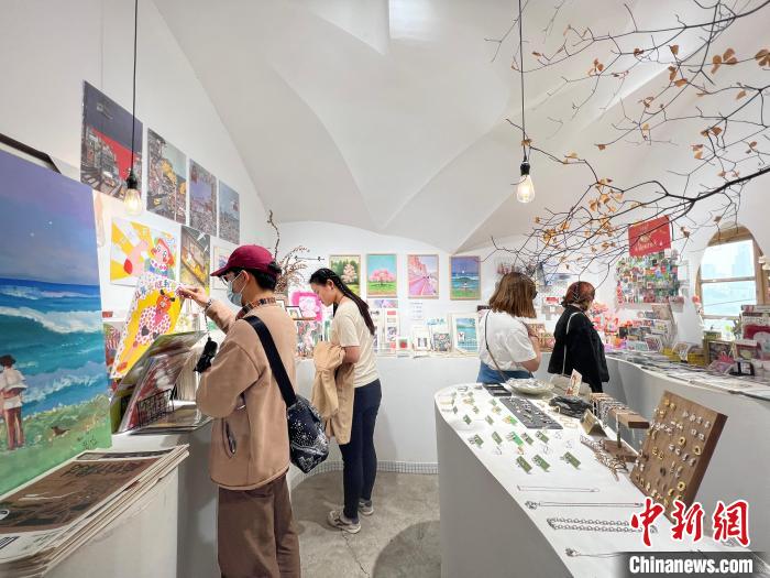 圖為(wei) 藝術品商店內(nei) ，顧客挑選插畫作品。　鍾旖 攝