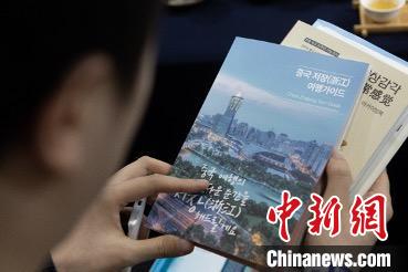 參展觀眾(zhong) 閱讀浙江文旅手冊(ce) 。　丁振哲 攝