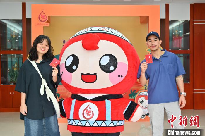 圖為(wei) 泰國留學生手持獻血證與(yu) 人偶合影。　俞靖 攝