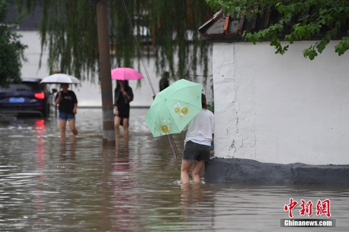 7月31日，市民行走在雨中的北京房山區瓦窯頭村。北京市氣象台當日10時發布分區域暴雨紅色預警信號。北京市水文總站發布洪水紅色預警，預計當日12時至14時，房山區大石河流域將出現紅色預警標準洪水。<a target='_blank' href='https://www.easyfundingllc.com/'><p  align=