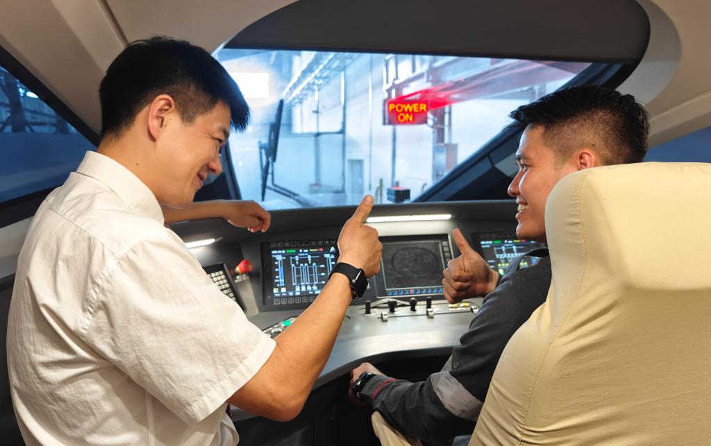8月25日，在印度尼西亞(ya) 萬(wan) 隆的雅萬(wan) 高鐵德卡魯爾動車所內(nei) ，中國師傅穆振（左）在向印尼火車司機塞蒂亞(ya) 萬(wan) 講解動車組出庫前的上電作業(ye) 。
