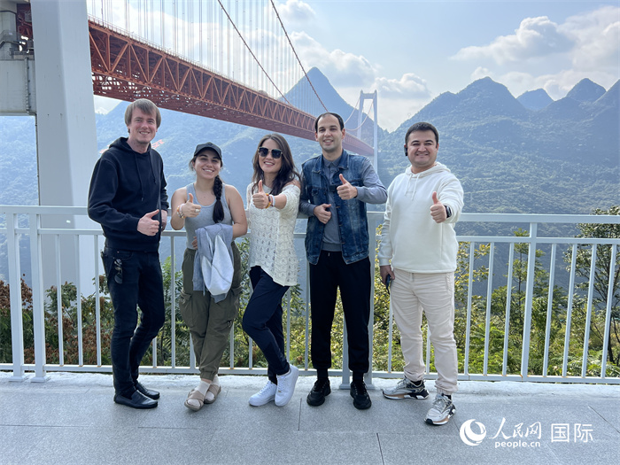 歐亞(ya) 國家記者在壩陵河大橋下合影，並給大橋“點讚”。人民網 花放攝