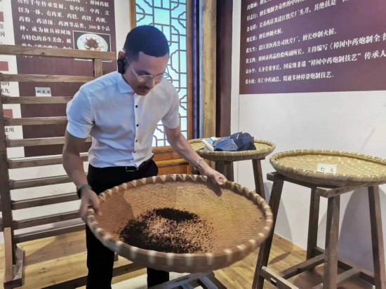 2023“一帶一路”媒體(ti) 合作論壇聯合采訪團團員在非遺文化展示館體(ti) 驗中藥炮製技藝。（本報記者 黃超攝）