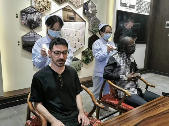 2023“一帶一路”媒體(ti) 合作論壇聯合采訪團團員在九牛草展示館體(ti) 驗艾灸。（本報記者 黃超攝）