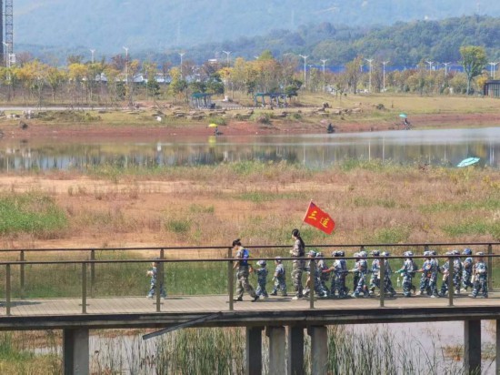　　10月24日，秋遊的幼兒(er) 園小朋友在老師帶領下走在清水塘公園裏的木橋上。本報記者 常雯宜攝