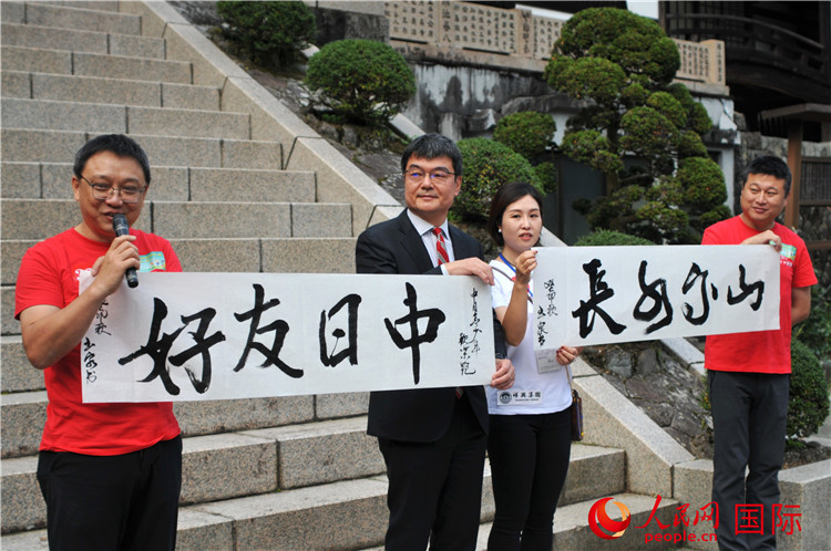 東(dong) 京中國文化中心主任羅玉泉展示其為(wei) 本次活動書(shu) 寫(xie) 的題詞“中日友好，山高水長”。人民網 蔣曉辰攝