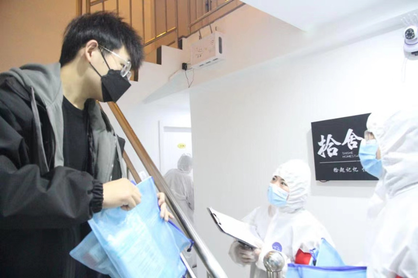 社區工作人員和誌願者身穿防護服上門送馬應龍大健康防疫包。徐帥攝