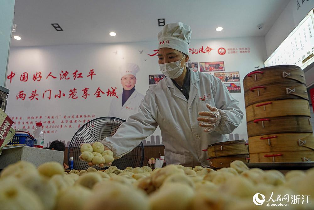 3月31日，在浙江省嵊州市甘霖鎮，嵊州小吃從(cong) 業(ye) 者沈紅平把蒸熟的小籠包晾涼，打包冷藏售賣。人民網 章勇濤攝