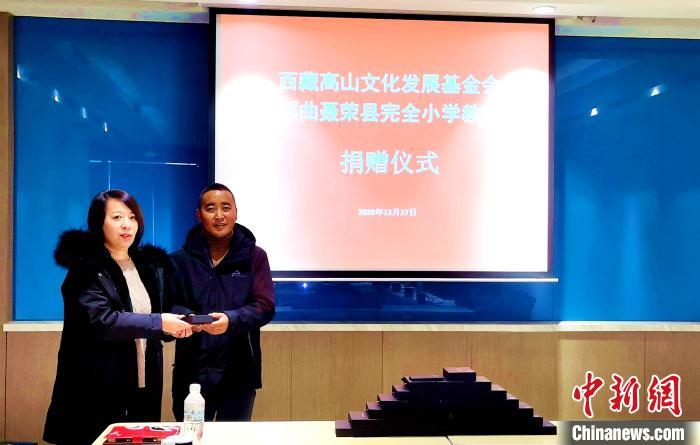 圖為(wei) 西藏高山文化發展基金會(hui) 理事長溫麗(li) 向聶榮縣完全小學負責人捐助儀(yi) 器。　於(yu) 賓 攝