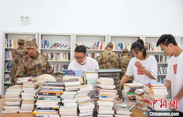 圖為(wei) 誌願者們(men) 和邊防戰士整理圖書(shu) 。　劉曉東(dong)  攝