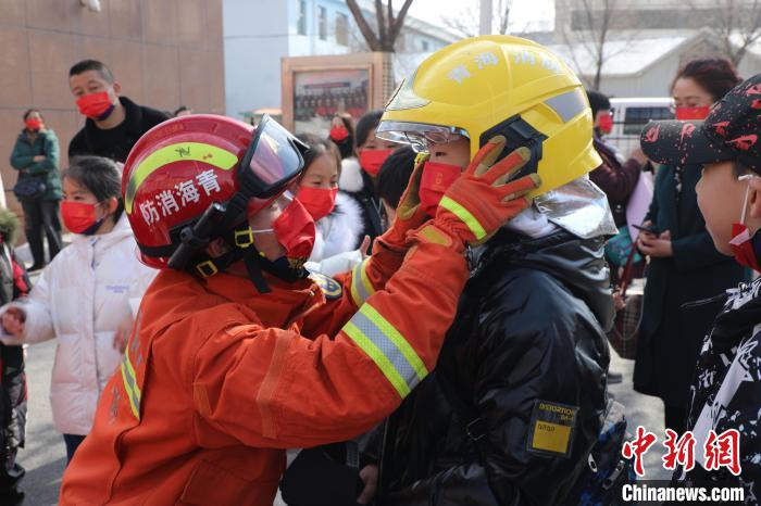 圖為(wei) 小朋友體(ti) 驗試穿消防滅火防護服。　楊龍建 攝