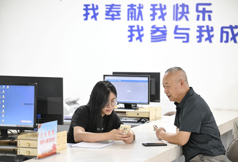 2024年6月20日，在寧夏銀川市金鳳區長城花園社區黨(dang) 群服務中心，工作人員幫助居民辦理業(ye) 務。圖片來源 新華社