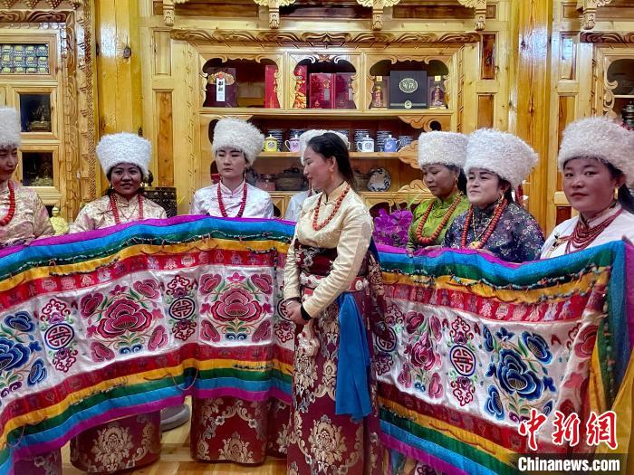 圖為(wei) 女性展示村民自發繡製的“百米五彩哈達”。　李玉峰 攝