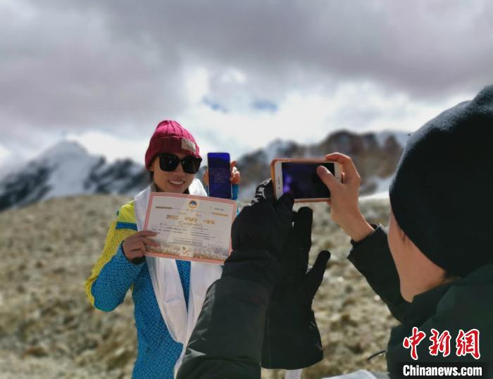 圖為(wei) 5日，登頂洛堆峰的登山者獲得西藏自治區登山協會(hui) 頒發的登頂證明。　張偉(wei)  攝