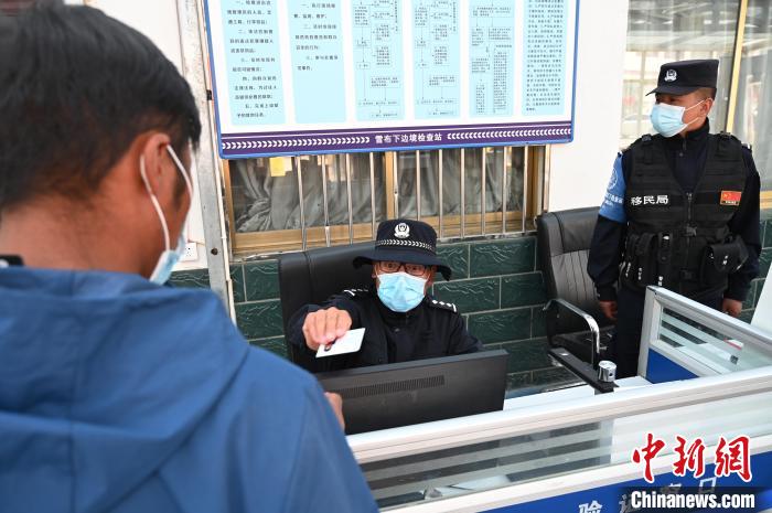圖為(wei) 移民管理警察登記完身份信息後將證件歸還給行人。　趙朗 攝