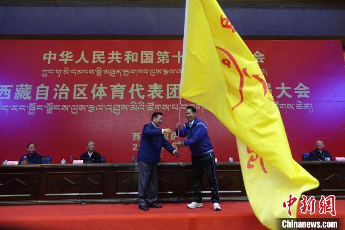 西藏自治區副主席甲熱·洛桑丹增授代表團團旗，西藏自治區體(ti) 育局局長尼瑪次仁接旗。　冉文娟 攝