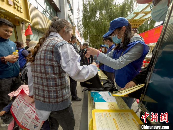圖為(wei) 誌願者為(wei) 市民發放網絡安全宣傳(chuan) 手冊(ce) 。　謝牧 攝