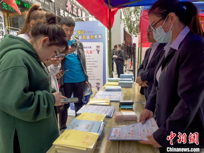圖為(wei) 工作人員正在向路過市民介紹國家反詐中心軟件的功能。　謝牧 攝