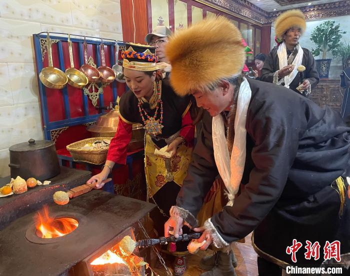 圖為(wei) 人們(men) 在火上烤節日美食“結達”。　冉文娟 攝