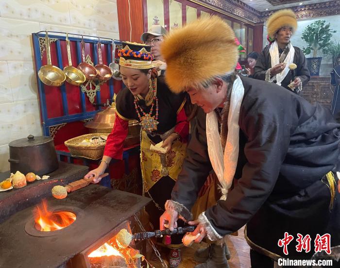 圖為(wei) 人們(men) 在火上烤節日美食“結達”。　冉文娟 攝