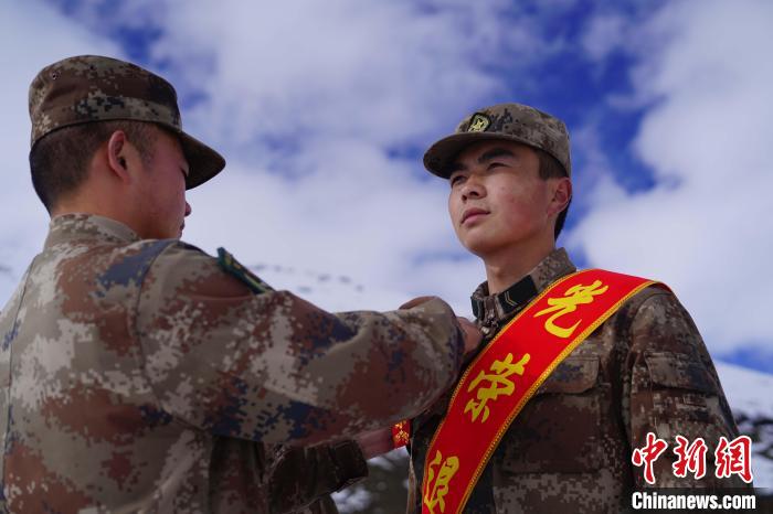 排長王朝偉(wei) (圖左)給退伍老兵佩戴大紅花。　西藏山南軍(jun) 分區某團供圖