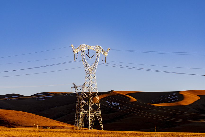 阿裏地區的曠野上，電力鐵塔在夕陽下熠熠生輝。