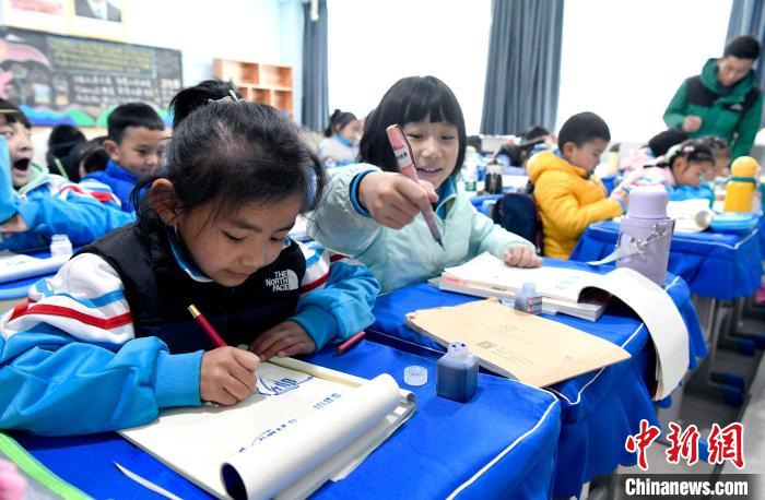 3月14日，西藏拉薩市第一小學一年級六班學生白瑪朗珍(圖左)在藏語文課上書(shu) 寫(xie) 藏文。　李林 攝