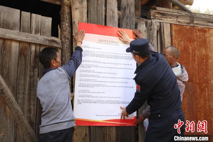 圖為(wei) 亞(ya) 東(dong) 邊檢站民警與(yu) 駐地邊民群眾(zhong) 共同張貼國家安全知識教育海報。　亞(ya) 東(dong) 邊檢站 供圖