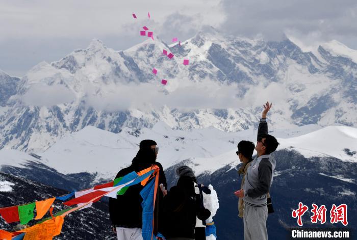 圖為(wei) 5月14日，遊客在西藏林芝色季拉山觀景台拋灑“隆達”(風馬旗，藏族民眾(zhong) 的一種祈福方式)。　李林 攝
