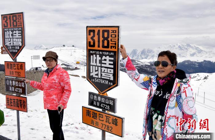 圖為(wei) 5月14日，西藏林芝色季拉山觀景台，遊客與(yu) 南迦巴瓦峰合影。　李林 攝
